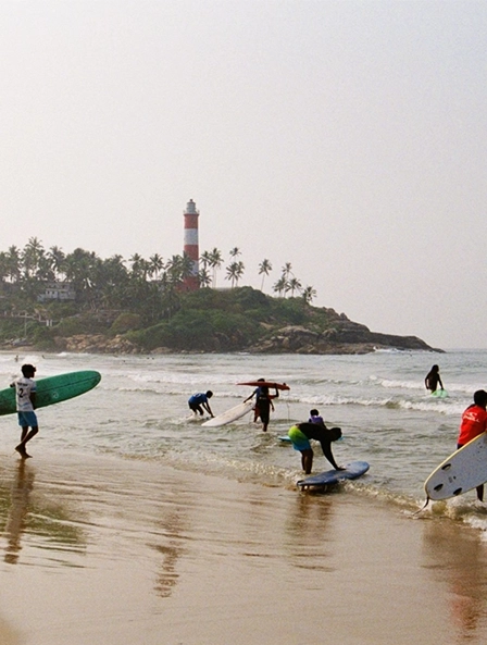 View of Kovalam Beach with surfers riding waves
